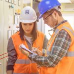 Dos personas con equipo de seguridad examinándola construcción de sistemas eléctricos