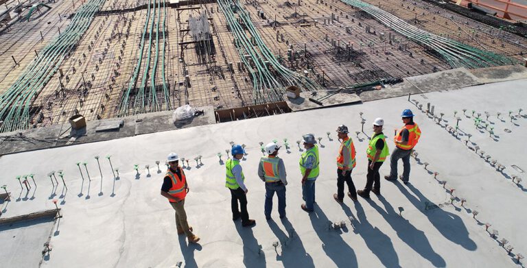 Un grupo de trabajadores eléctricos parados en un sitio de construcción.
