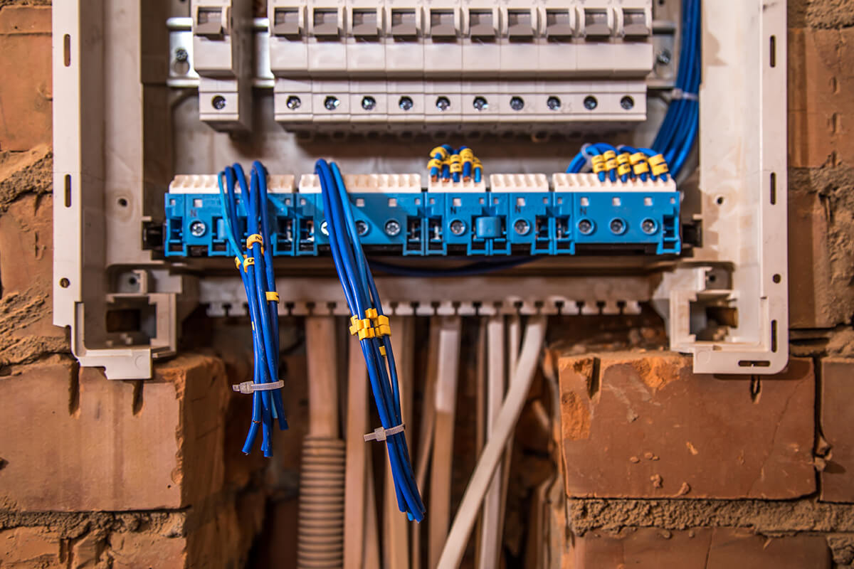 Panel eléctrico con cables y alambres en pared de ladrillo.