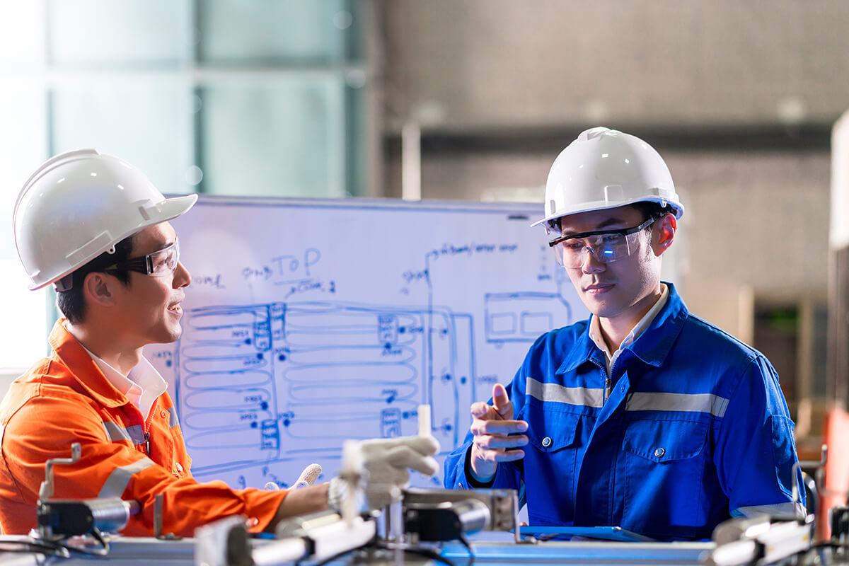 Dos trabajadores industriales conversando en el lugar de trabajo.