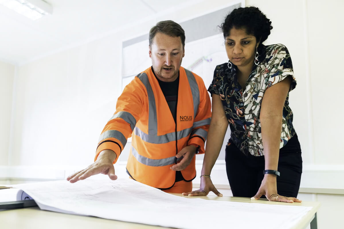 Un hombre y una mujer en una oficina revisando un plano.